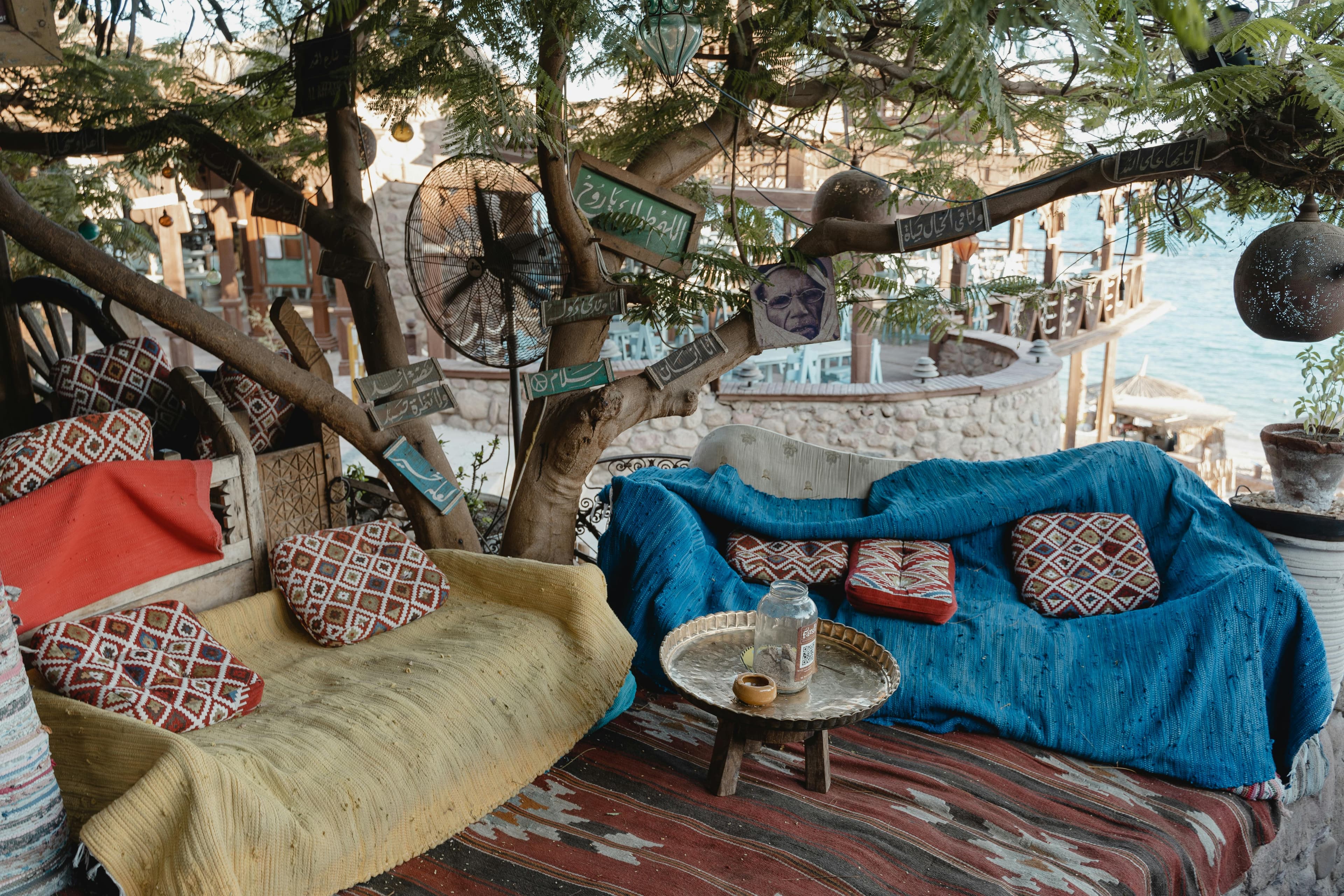 Rustic outdoor seating area with colorful textiles and patterned pillows, showcasing bohemian summer decor trends for balconies and patios.